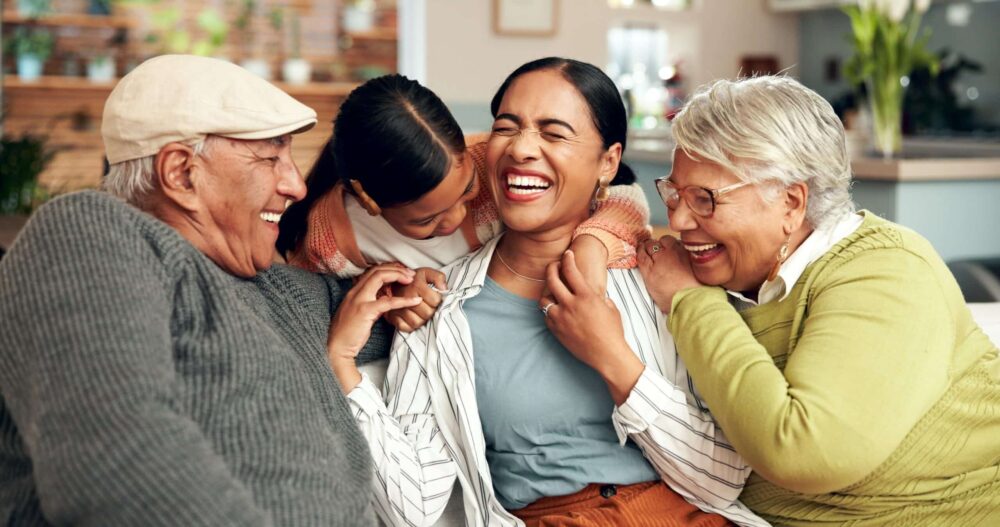 wayzata family dentistry - gernational family of 4 sitting and laughing on a couch.