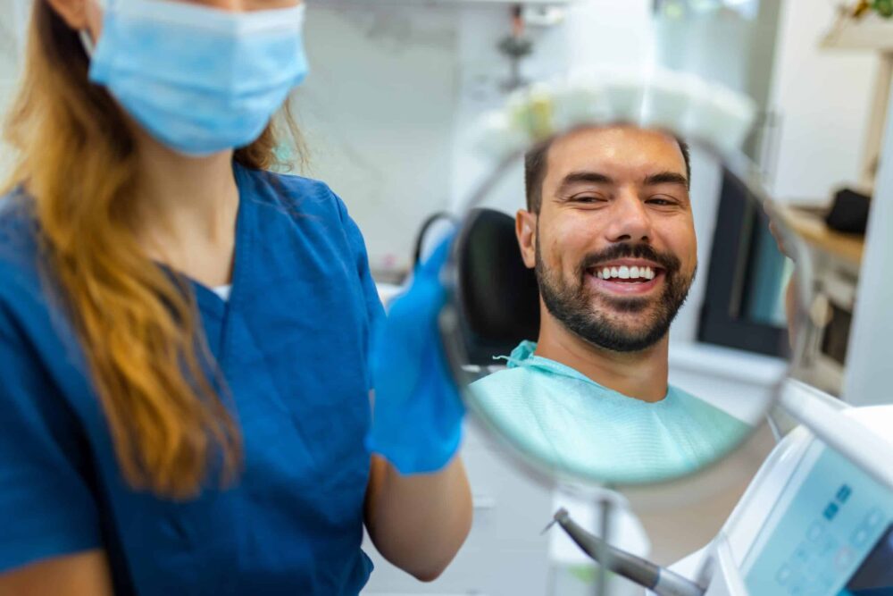 wayzata dentist - Man sitting in a dental chair looking at himself in a mirror.