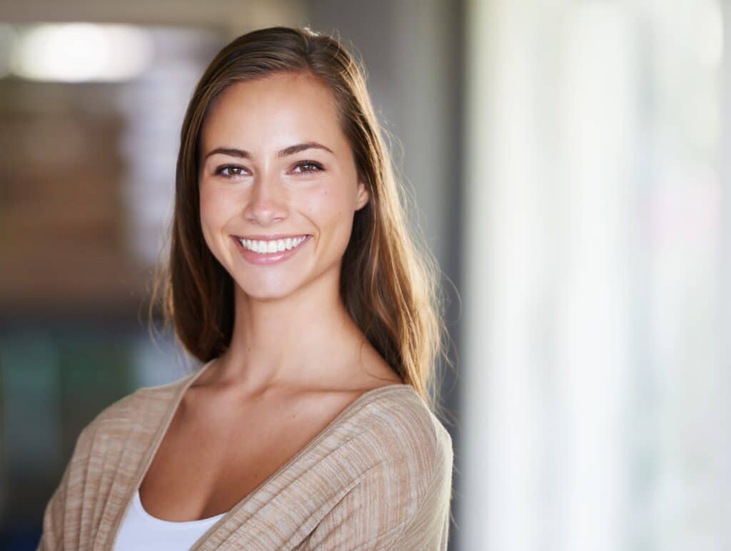 Cosmetic Dentist in Wayzata - young lady with brown haird and tan shirt smiling.